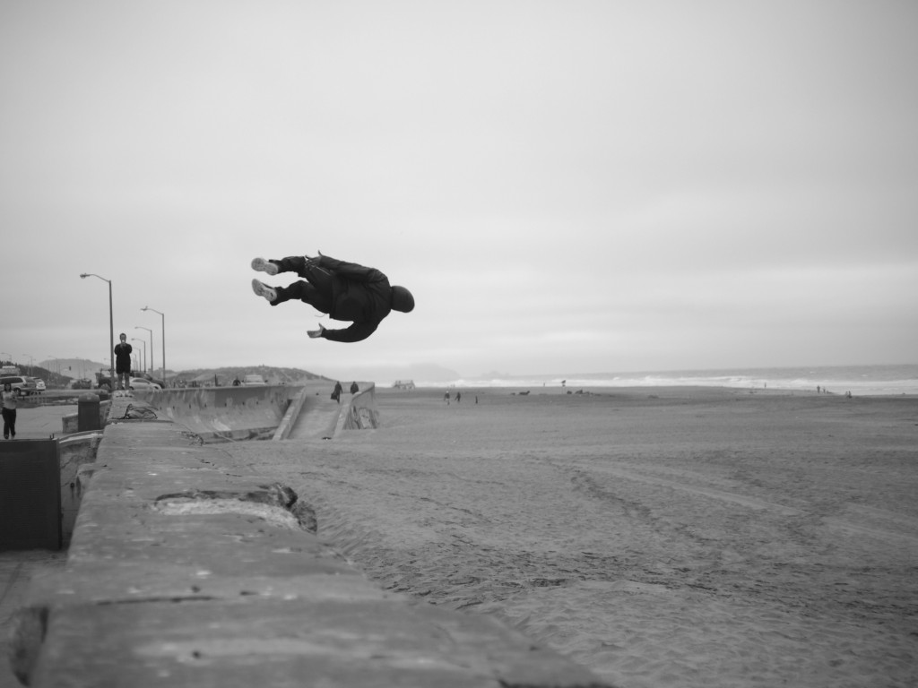 Young guy leaping the sea-wall at Ocean Beach, San Francisco